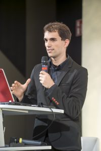 Foto eines Vortragenden mit Mikrofon in der Hand